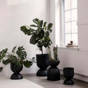 Natürlich wohnen: wirklich coole Ideen mit Holz, Glas & Erdtönen 7 Dunkle, sanduhrförmige Ferm Living Hourglass Pot Pflanzenkübel in verschiednen Höhen in einem weißen Innenraum.