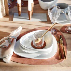 LIND DNA Leder-Tischsets machen aus jedem Tisch ein Erlebnis. Hier in sandigem Braun und eingedeckt mit weißem Geschirr, goldenem Besteck und passender Stoffserviette.