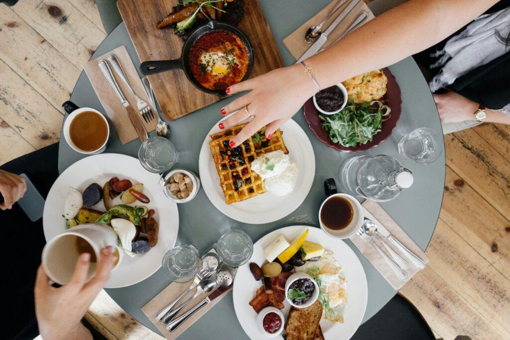 7 frische Ideen für ein Frühstück im Freien 1 Frühstück im Freien an einem runden Tisch. Mit Waffeln und verschiedenen herzhaften Speisen.