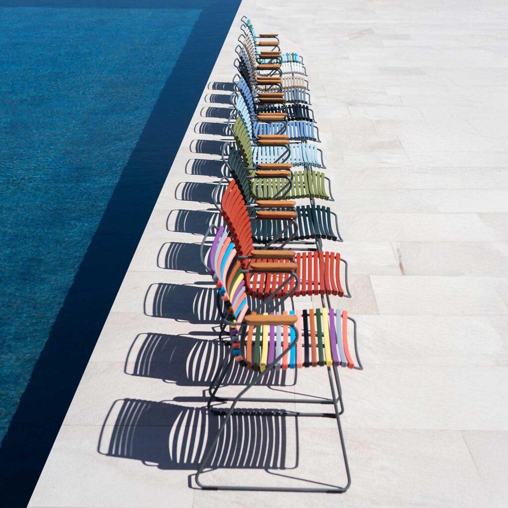 Outdoor Living: Design-Ideen für Balkon, Terrasse & Garten 2 HOUE Click Gartensessel in verschiedenen Farben, hintereinander aufgereiht an einem Pool.