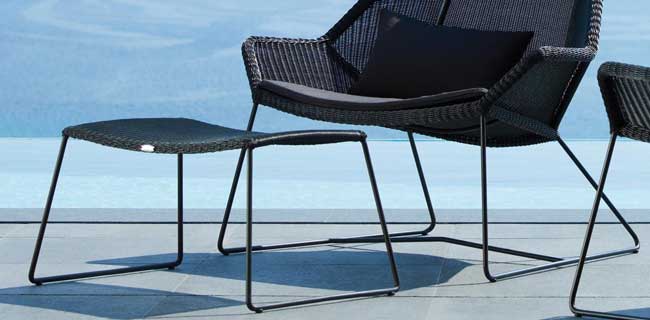 Cane-line Hocker Breeze schwarz mit Stuhl draußen